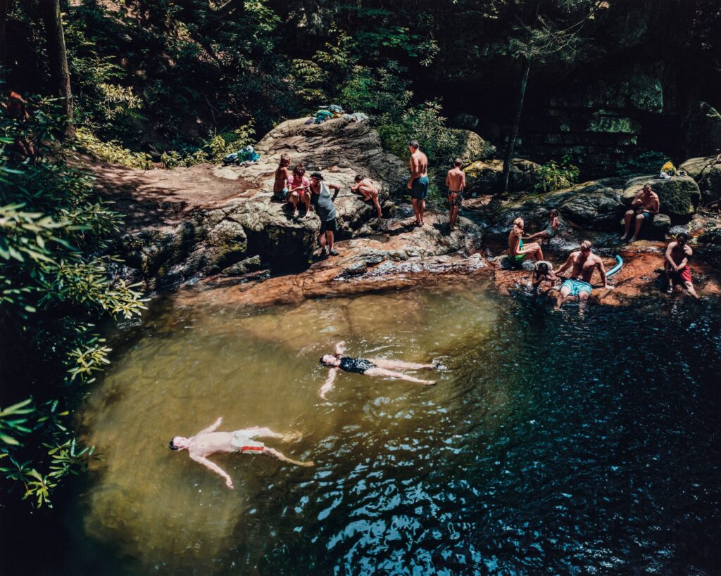 People swimming and resting on rocks at Blue Hole in Carter County, Tennessee.